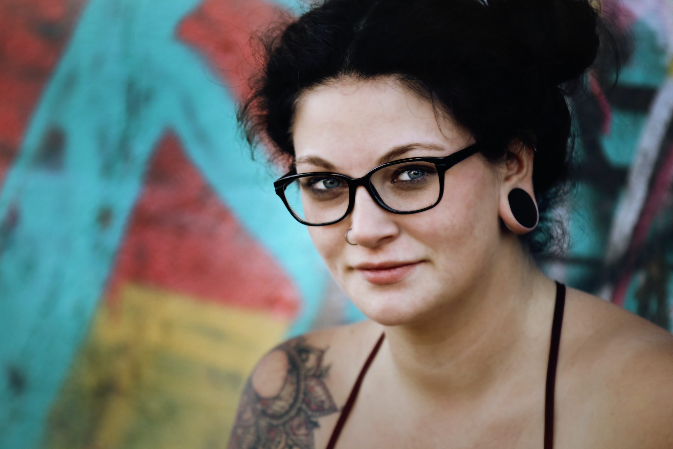 Dark haired girl with glasses a nose ring and arm tattoo