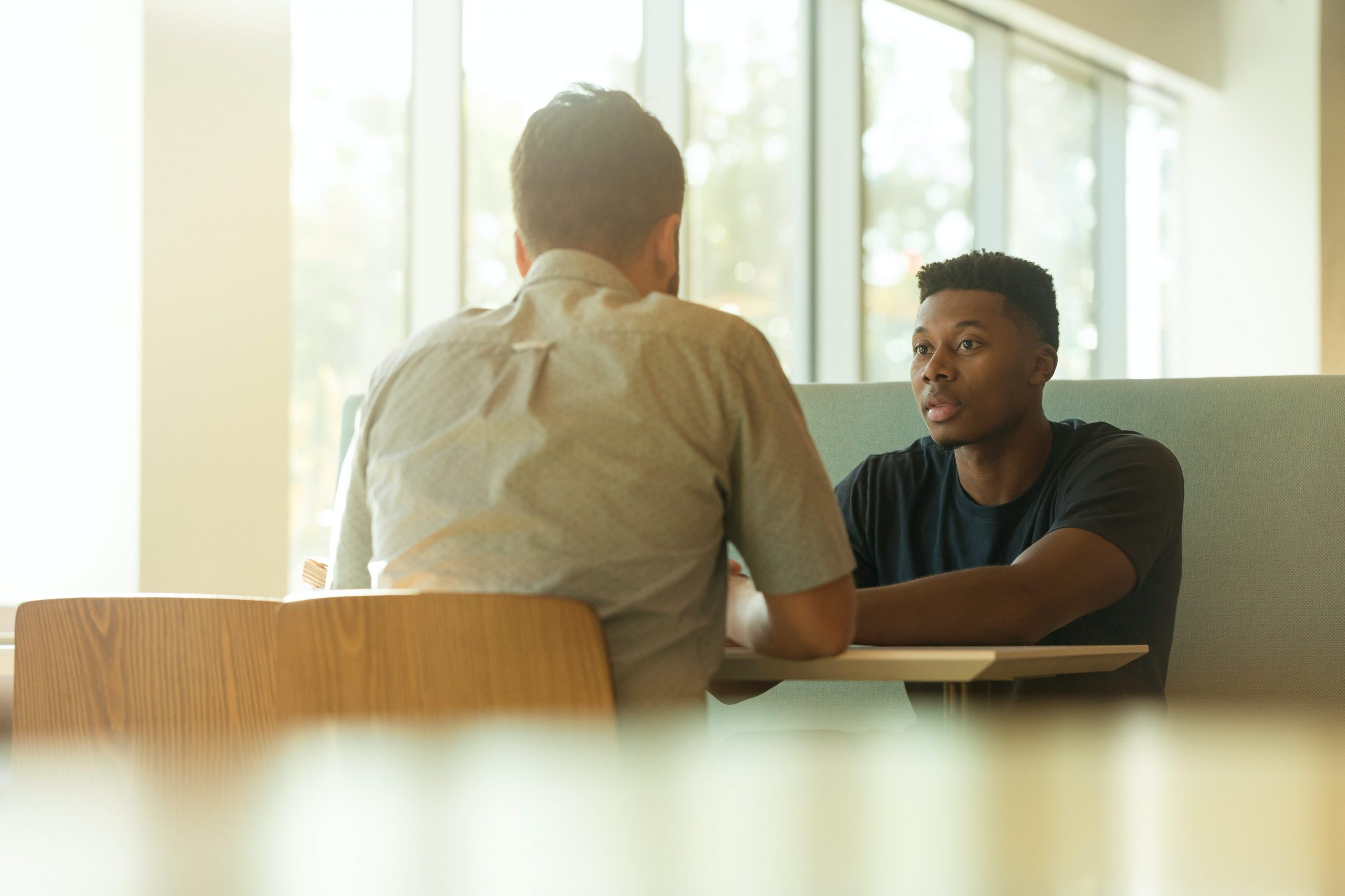 Two men in an office booth talking.