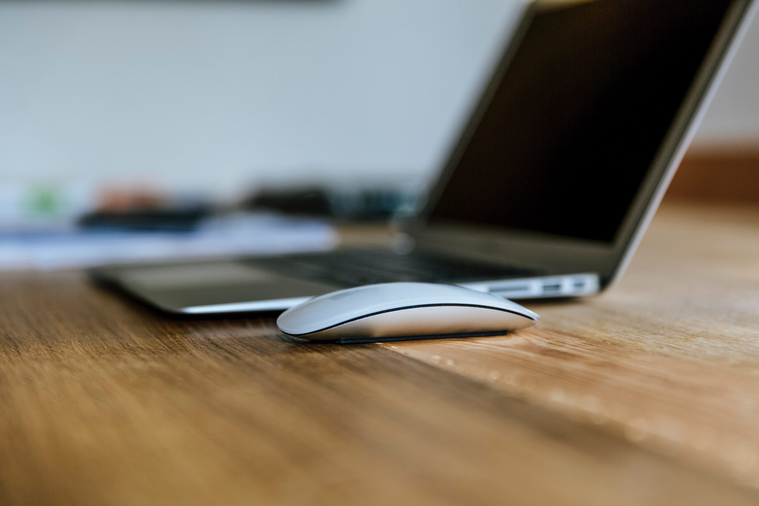 Laptop and mouse sat on a wooden table