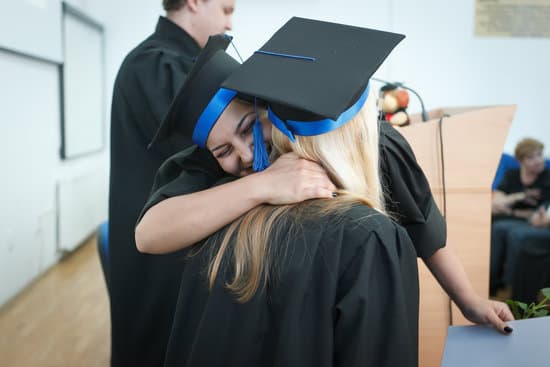 Two women in graduation hats and gowns hugging