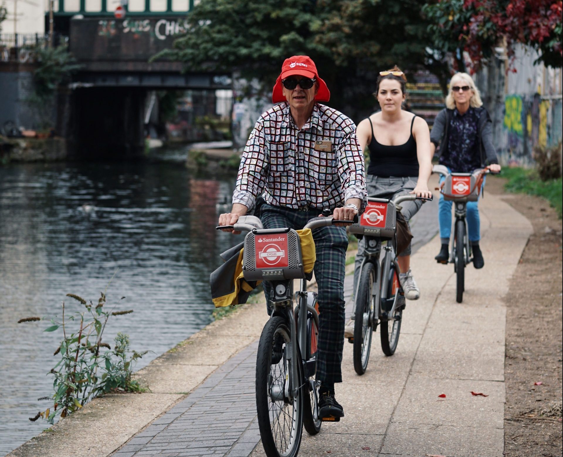 Three people on Santander bikes riding next to a river