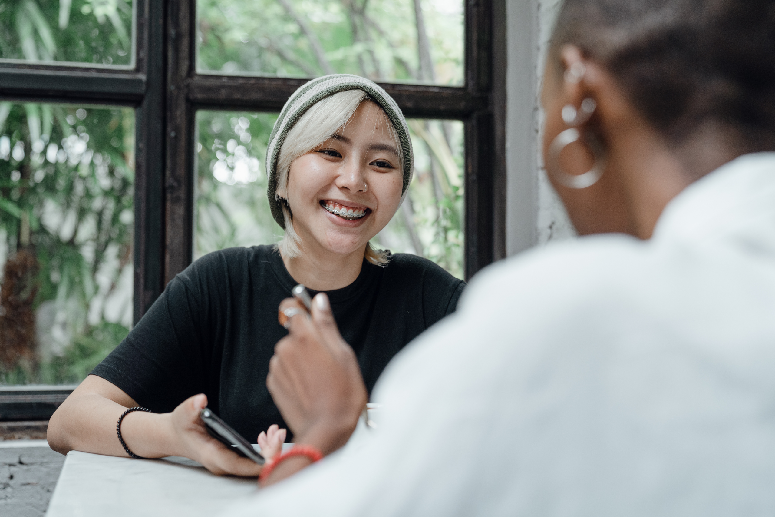 Woman in hat chatting to person with back to them